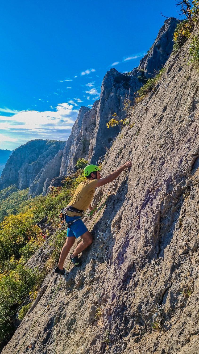 Escalador en una pared de roca caliza con el valle al fondo