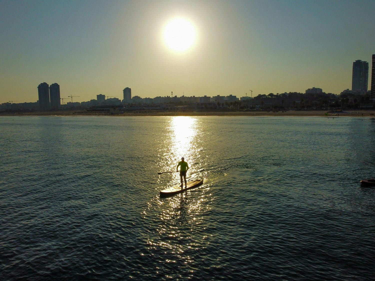 Paddle surf a vista de pájaro sobre el reflejo del sol