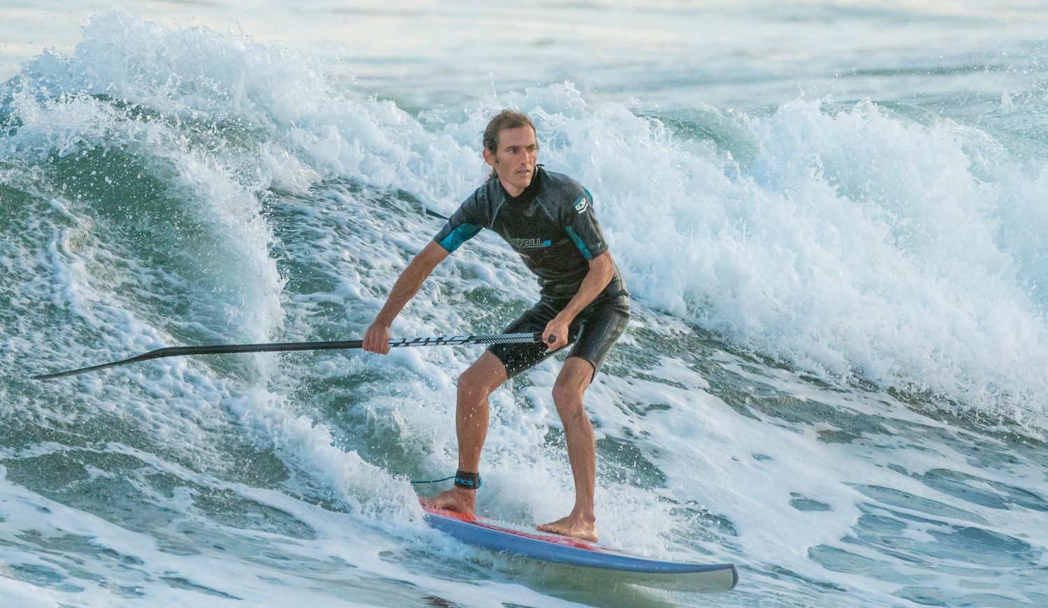 Surfista de SUP deslizándose por una ola